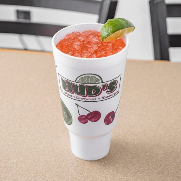 A Hud's cherry limeade with crushed ice and a lime wedge in a white styrofoam cup.