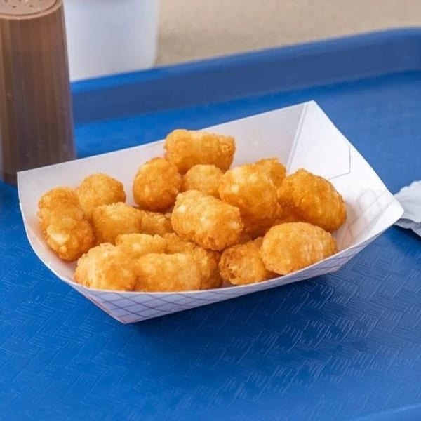 A paper tray filled with golden-brown tater tots sits on a blue textured surface at Hud's.