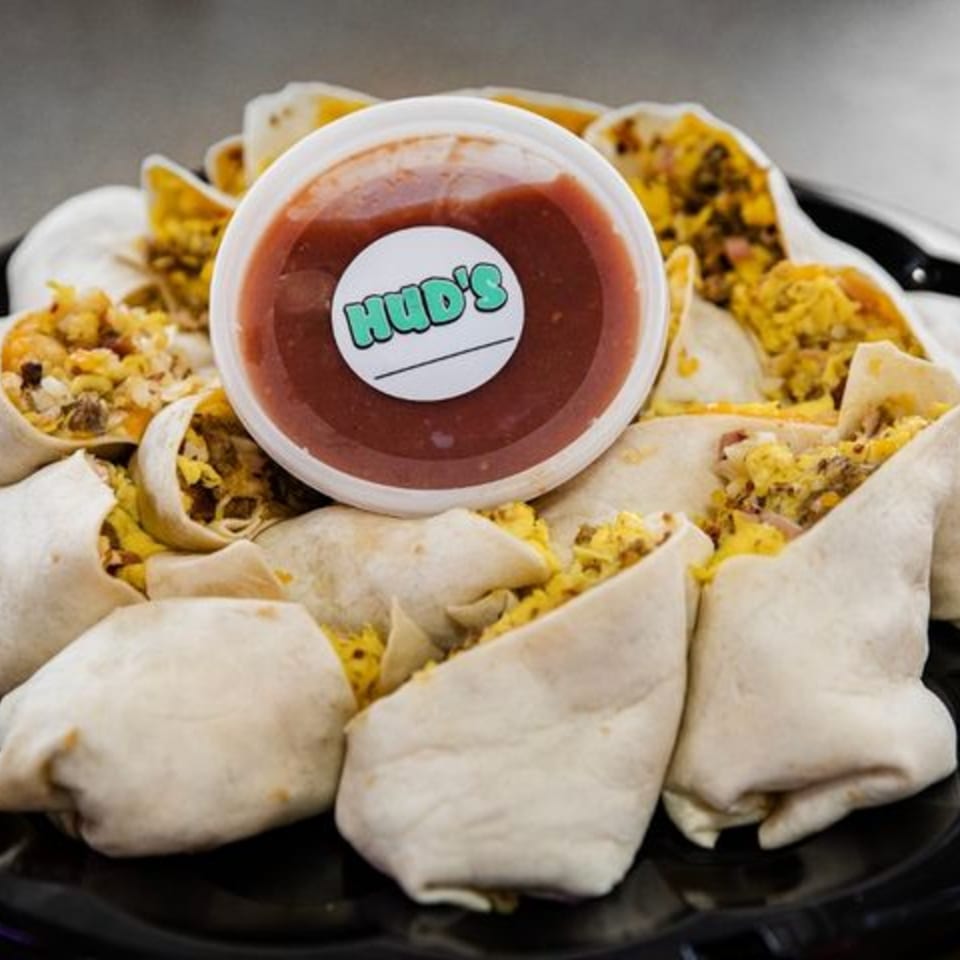Hud's breakfast burritos with scrambled eggs and salsa on a black platter.